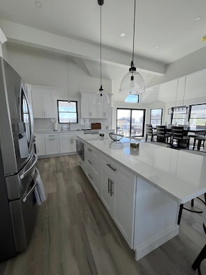 A modern kitchen with white cabinetry, a large island, and pendant lighting.