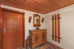 Uma porta de madeira, um armário de madeira com espelho, luminárias fixadas na parede e suportes para esquis.