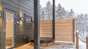 A wooden cabin with a glass door, a hot tub, and a wooden deck.