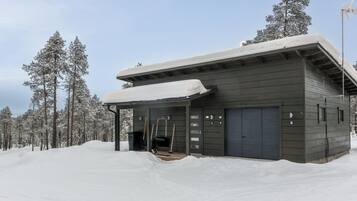 Moderni rakennus, jossa on katettu sisäänkäynti, suuret autotallin ovet ja lumipeitteinen katto.