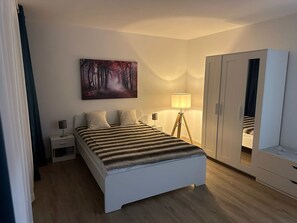 Relax in a serene bedroom with a neatly made bed, bedside table, and large wardrobe.