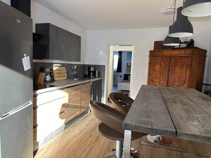 Kitchen features a dining table, wooden cabinet, and stainless steel sink.