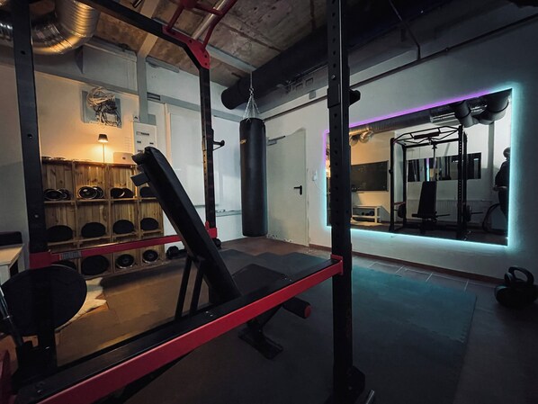 A gym with weightlifting equipment, a bench, and a mirrored wall. - Ferienwohnung Seeblick, 50 qm, 1 Sep. Schlafzimmer mit Balkon (Seeon-Seebruck)