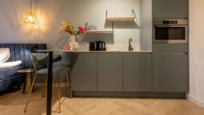 Une cuisine moderne équipée d’un four encastré, d’une machine à café et d’une étagère à verres.