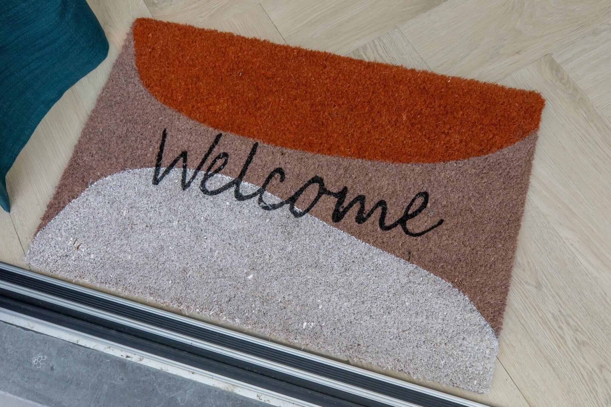 A welcome mat with the word "Welcome" in black letters.