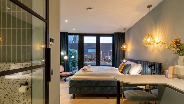 Une chambre d’hôtel moderne dotée d’un grand lit, d’un coin repas et offrant une vue sur l’extérieur.