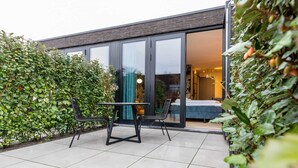 A modern patio with a table and chairs, surrounded by dense foliage. - Romantic Getaway with Garden (Koudekerke)