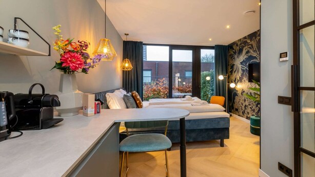 A modern living room with a sofa, a dining table, and a coffee machine. - Romantic Getaway with Garden (Koudekerke)