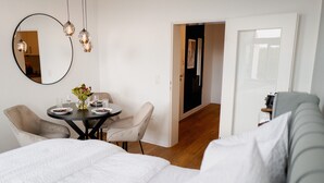 Ein Hotelzimmer mit Bett, Esstisch mit Stühlen, Spiegel und einer Tür zu einem weiteren Raum.