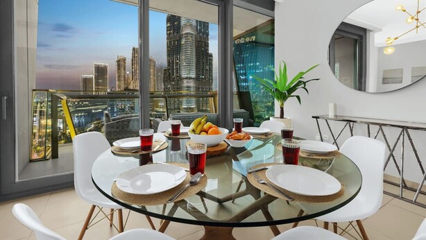A dining area with a glass table, white chairs, and a city view. - Downtown 3BR | Sleeps 9 | Balcony, Full Kitchen, Near Metro (Downtown)