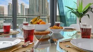 A dining table with a city view, fruit bowl, croissants, and red drinks. - Downtown 3BR | Sleeps 9 | Balcony, Full Kitchen, Near Metro (Downtown)