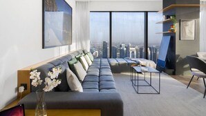A modern living room with a grey sofa, a coffee table, and a city view through large windows. - Luxury 3BR at Marina Gate | Stunning Sea Views, Pool, Gym & Prime Location (Marina)