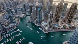 A high-rise urban area with modern skyscrapers, a marina with boats, and a waterfront view. - Luxury 3BR at Marina Gate | Stunning Sea Views, Pool, Gym & Prime Location (Marina)