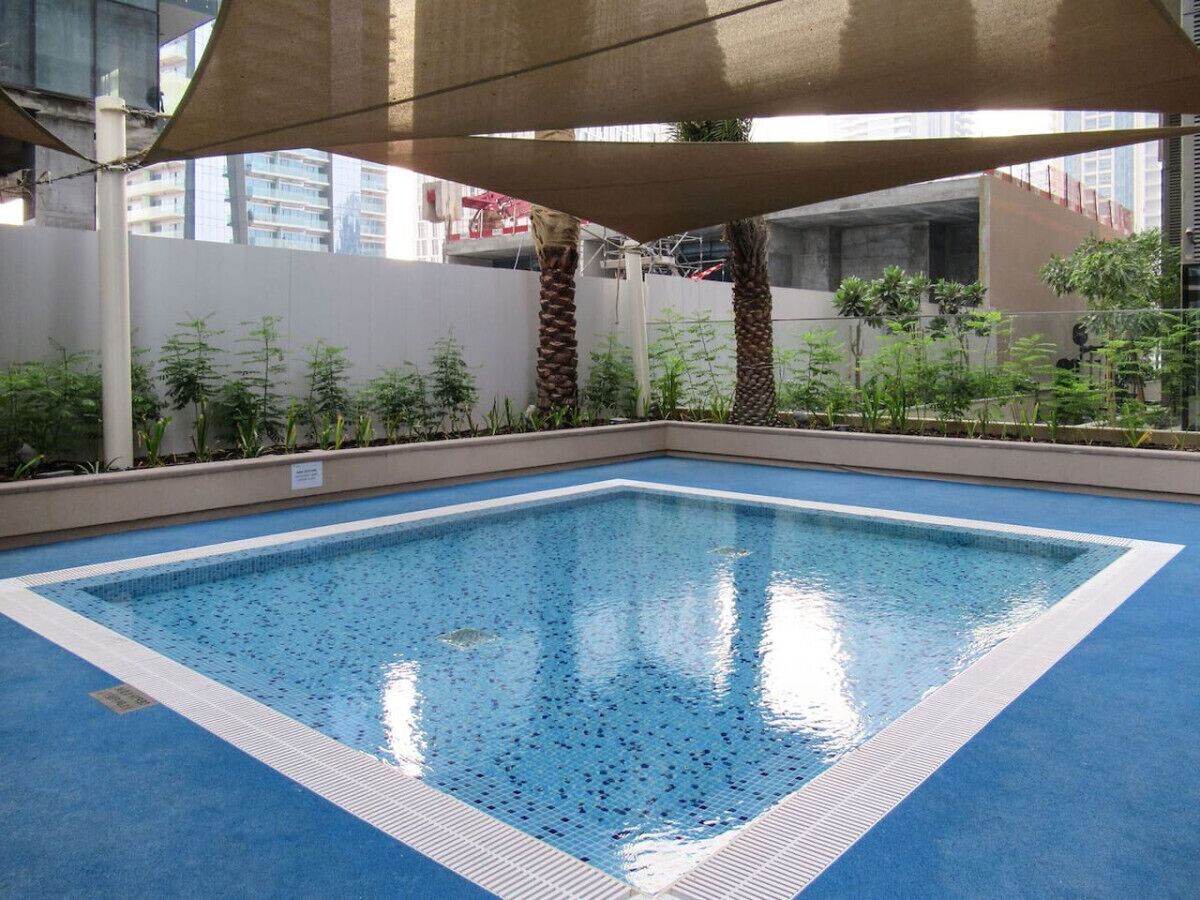 Una piscina interior rectangular con suelo de azulejos azules y borde blanco.