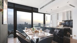 A modern dining area with a city view, a kitchen with marble countertops, and a large island. - Luxury 3BR at Marina Gate | Stunning Sea Views, Pool, Gym & Prime Location (Marina)