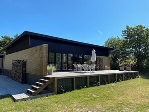 A modern house with a deck, outdoor furniture, and a staircase leading to the entrance. - Cottage with 400 m to the water and the marina (Østerby Havn)