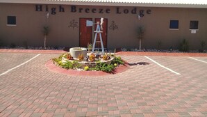 The exterior of High Breeze Lodge with a paved driveway and a landscaped garden area in front. - High Breeze Lodge (Upington)