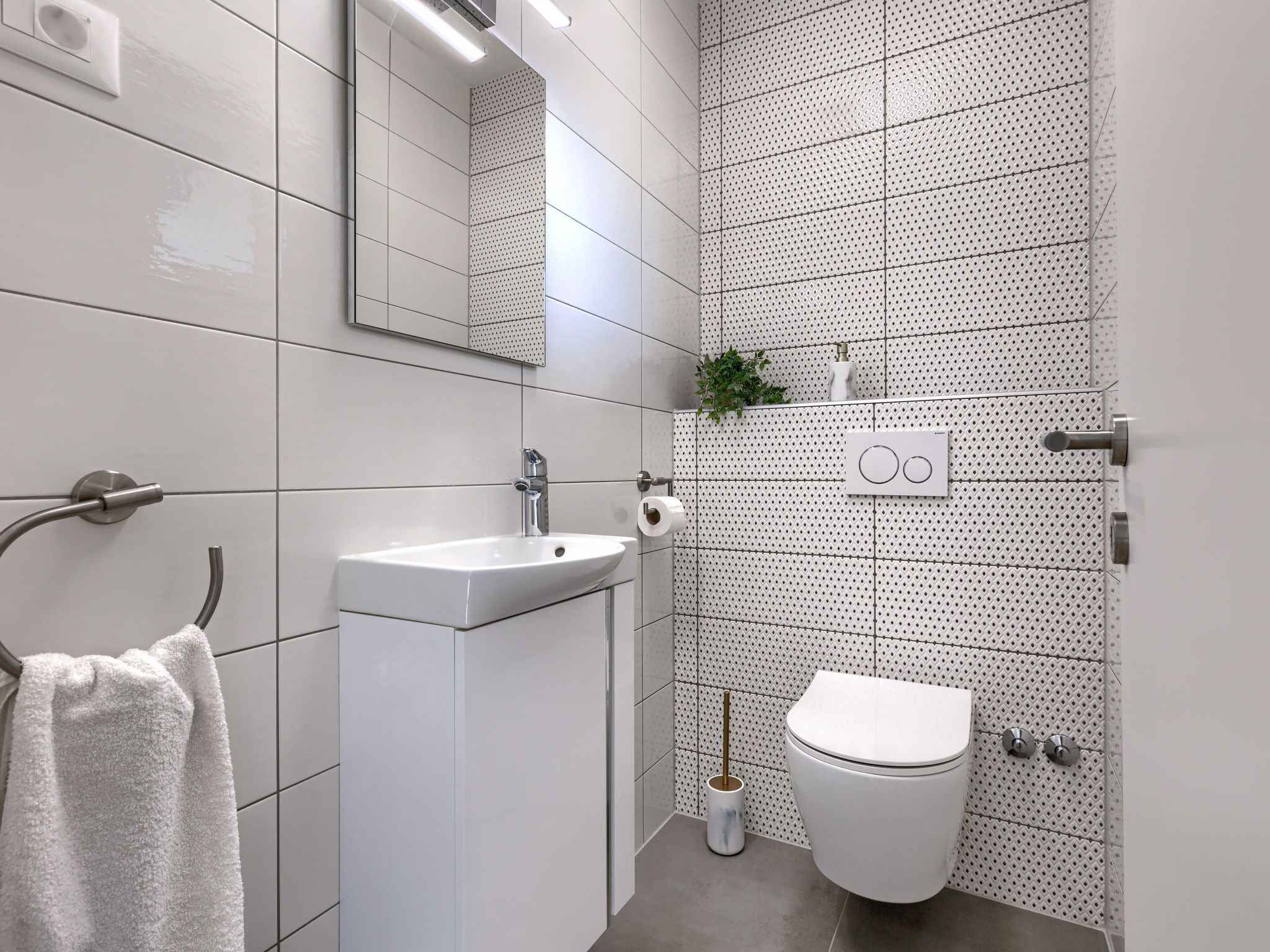 A modern bathroom with a white sink, toilet, and a towel rack.