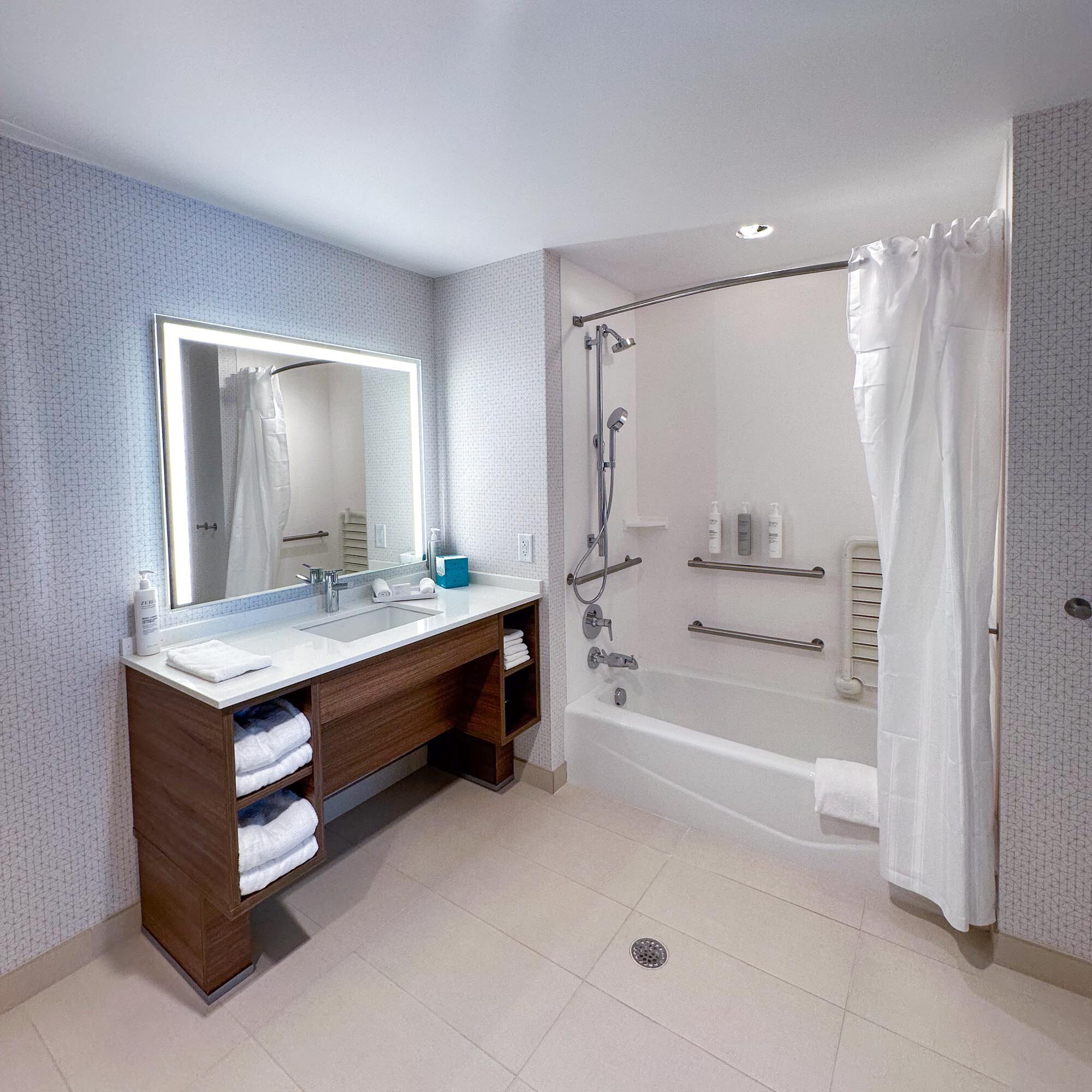 Une salle de bain moderne avec un grand miroir, deux vasques, une douche et une baignoire.