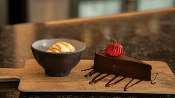 Un postre con un trozo de chocolate y un bol de helado sobre una tabla de madera.