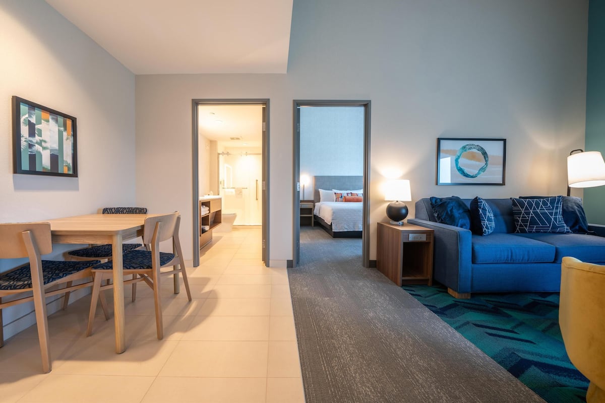 Habitación de hotel con comedor, sofá y cama.