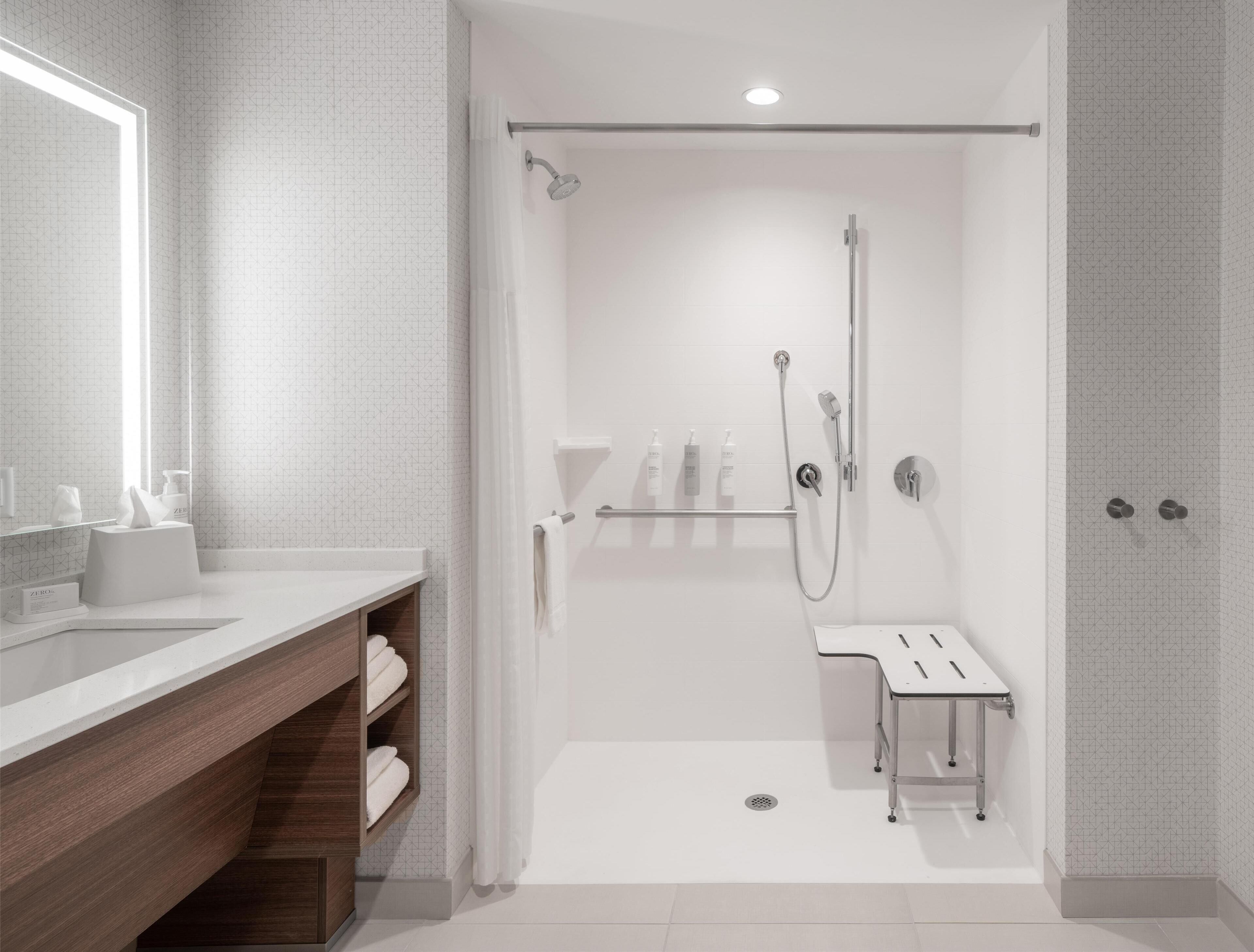 A modern bathroom with a shower, a vanity with a mirror, and a towel rack.
