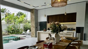 A modern dining area with a pool view, a stone pillar, and a kitchen with a microwave and water dispenser. - Ocean view 2-bedrooms Yudistira villa 50m from the beach (Bali)