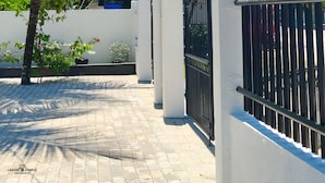 A gated entrance with a sign for MP Apartments, a paved pathway, and palm trees. - MP Apartments Leyte (Hindang)