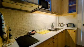 A kitchen with white subway tiles, a stainless steel sink, a microwave, and wooden cabinets.