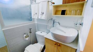 Ein Badezimmer mit Toilette, Waschbecken und einem Holzschrank.