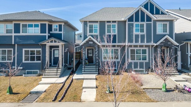 A row of two-story townhouses with a central entrance, front steps, and a small front yard with young trees. - Suburban Restful Retreat 1BD 1BA, WiFi, Laundry (Calgary)