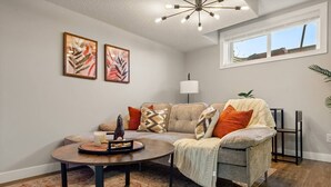 A living room with a sofa, a coffee table, and two framed artworks on the wall. - Suburban Restful Retreat 1BD 1BA, WiFi, Laundry (Calgary)