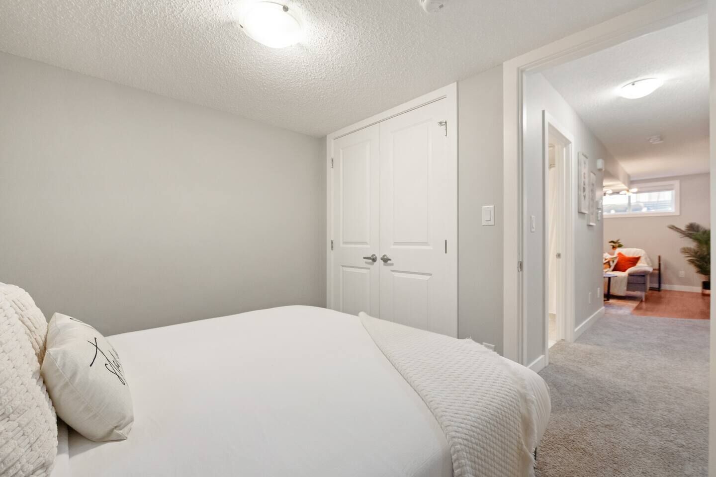 Un dormitorio con una cama grande, paredes blancas y una puerta que da a otra habitación.