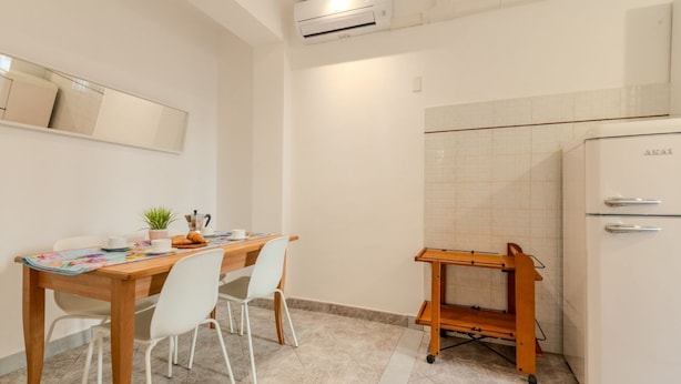 Una cucina compatta con zona pranzo, un carrello e un frigorifero.