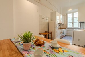 A modern kitchen with white cabinets, a dining table with a floral tablecloth, and a potted plant. - ToMo Apartment St. Peter's (Roma)