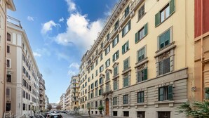 Une rue bordée d’immeubles à étages, dotés de balcons et de grandes fenêtres.