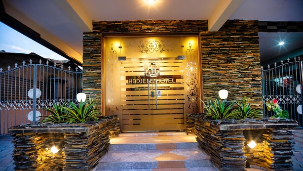 A hotel entrance with a stone facade, a metal gate, and a sign reading "HADJENS HOTEL." - HADJENS HOTEL (Mwanza)