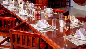 A dining area with wooden tables set for a meal, complete with plates, cutlery, and wine glasses. - HADJENS HOTEL (Mwanza)