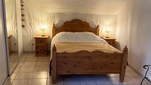 A bedroom with a wooden bed, two bedside tables with lamps, a large mirror, and a tiled floor. - Bel appartement duplex, terrasse , 2 min du lac ,4pers (Sévrier)