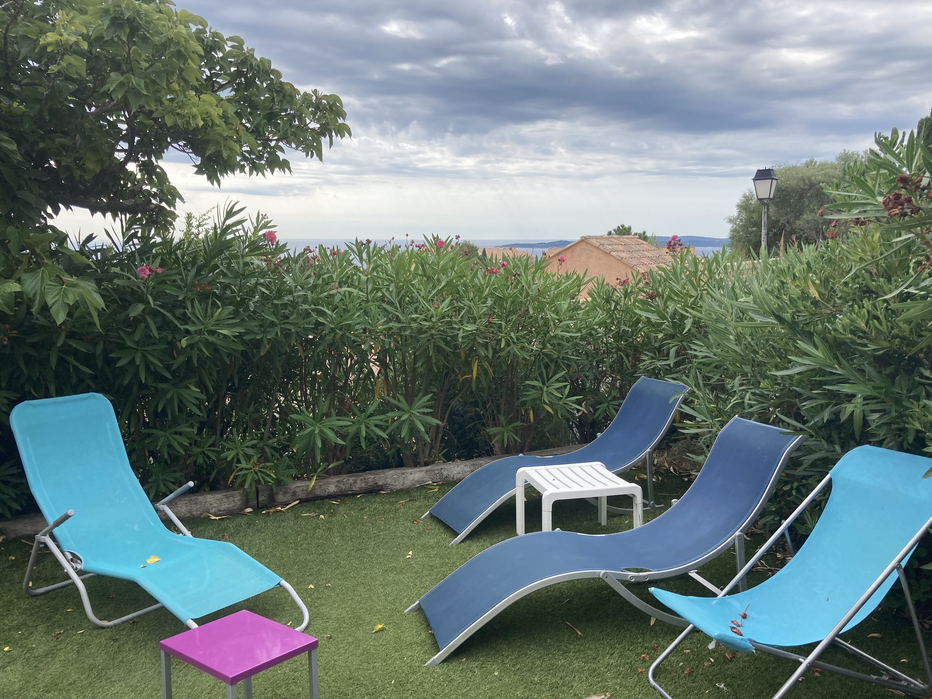 Una terrazza con poltrone relax e un piccolo tavolo, immersa nel verde e con vista su edifici in lontananza.