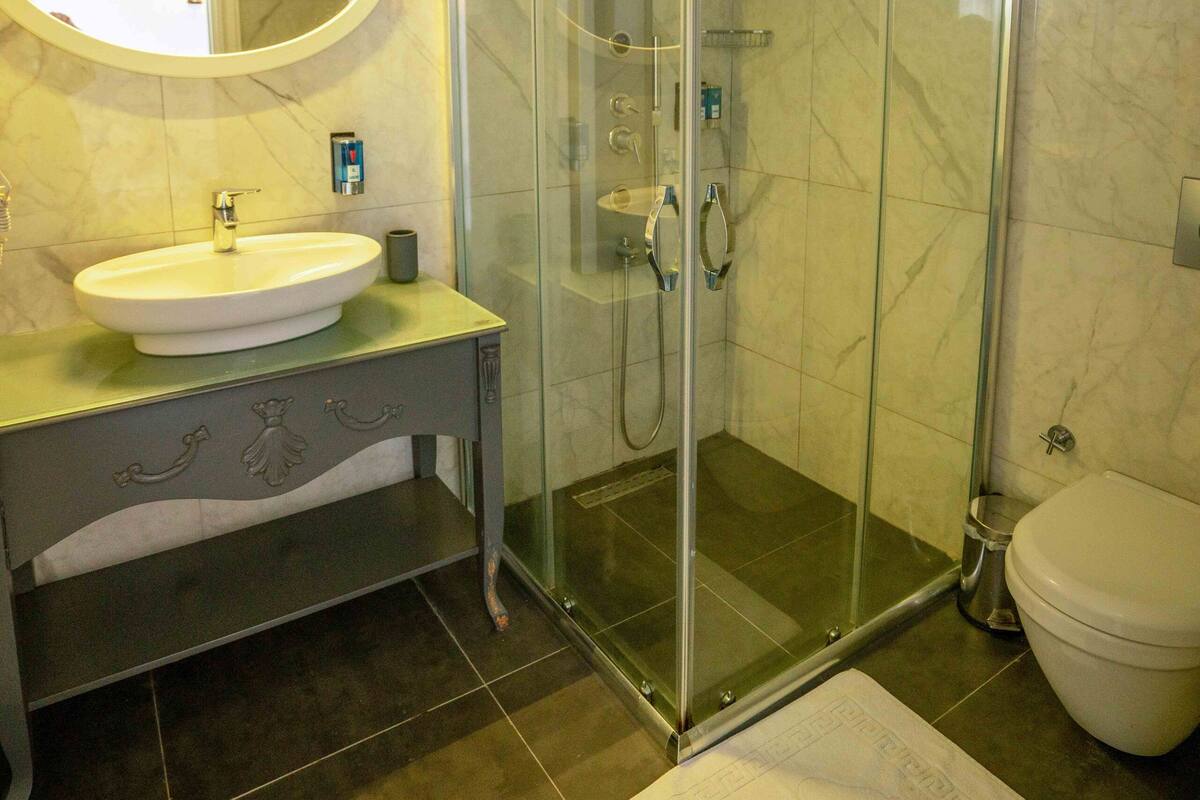 A bathroom with a glass-enclosed shower, a sink, and a toilet.