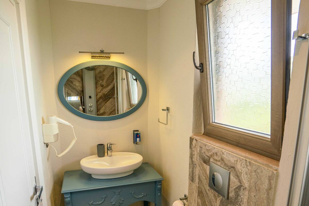 A bathroom with a white sink, blue vanity, and a toilet.