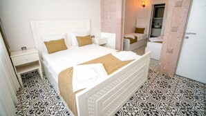 Ein Hotelzimmer mit einem großen Bett, einem Nachttisch, einem Kleiderschrank und einem durch eine offene Tür einsehbaren Badezimmer.