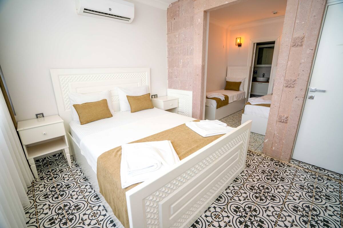 A hotel room with a large bed, a bedside table, a wardrobe, and a bathroom visible through an open door.