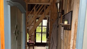 Un couloir étroit au plancher en bois, avec une armoire bleue et un escalier menant à l’étage supérieur.