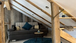 Un salon chaleureux, aménagé dans un style industriel, avec un canapé gris foncé, un tapis rond bleu et une petite table ronde.