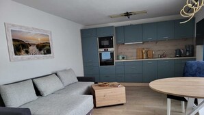 Un salon moderne avec un canapé gris, une table basse en bois et une table de salle à manger ronde.