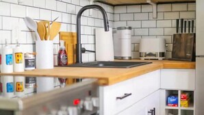 A modern kitchen with white cabinets, a black faucet, and a built-in oven. - Queens Suite 1BR Free Parking (St. John's)