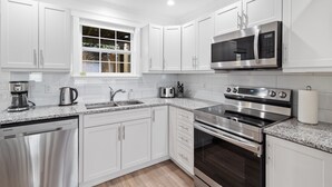 A modern kitchen with white cabinets, stainless steel appliances, a built-in oven, and a microwave. - Wood House King Bd 2 Queens Fire Pit (St. John's)