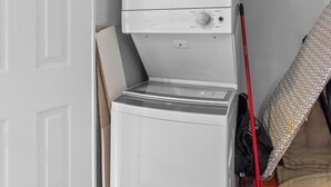 A compact laundry room with a washing machine, a dryer, and a storage area with cleaning supplies. - House Patrick  4Bd Loft Style Parking (St. John's)